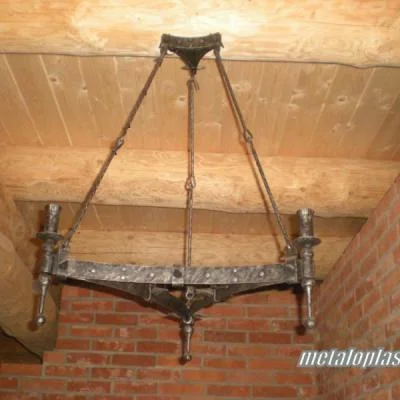 Trójkątna lampa wisząca na trzech zawiesiach. Misterne, ćwiekowane wykończenie z uchwytami na pochodnie do wnętrz średniowiecznych, karczm i pubów oraz do domów z bala.