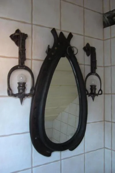 Designerskie kinkiety ścienne ze strzemion i lustro w kształcie chomonta, luksusowy komplet jeździecki.
