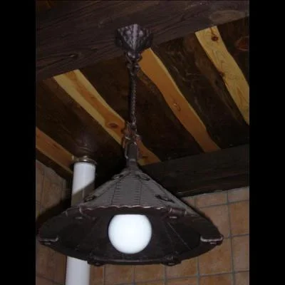 Masywna metalowa lampa sufitowa z nitowanym kloszem, rustykalne oświetlenie kierunkowe nad stół jadalniany.