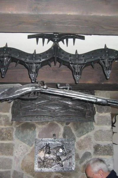 Monumentalna lampa wisząca z autorską repliką muszkietu, rzeźbiarska konstrukcja w barwie palonego metalu na łańcuchach do wnętrz rustykalnych