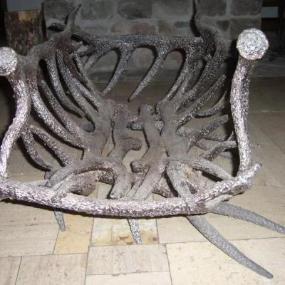 Artystyczny stojak kominkowy o rzeźbiarskiej strukturze przeplatających się metalowych poroży, unikatowe rękodzieło o głębokiej fakturze i surowym wykończeniu.