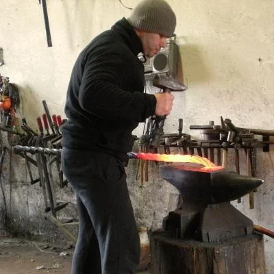 Kowal podczas kucia skrętnego rozgrzanej rury stalowej w temperaturze około 1100°C.